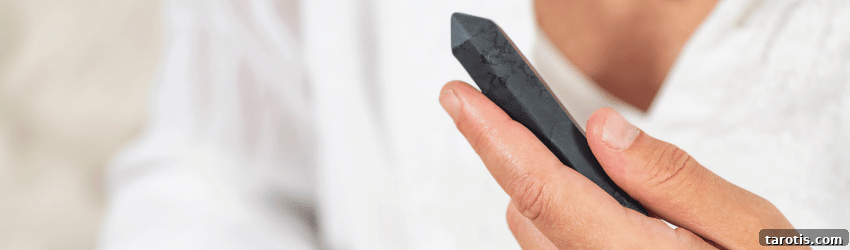 10 Healing Crystals to Help You Recover from a Breakup 2 A person holds an Obsidian crystal point in their hand.
