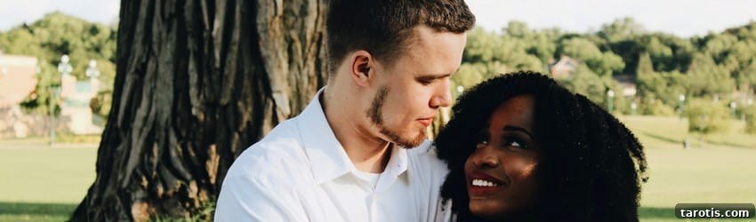 A couple looks at each other with love in their eyes while the sit under a tree.